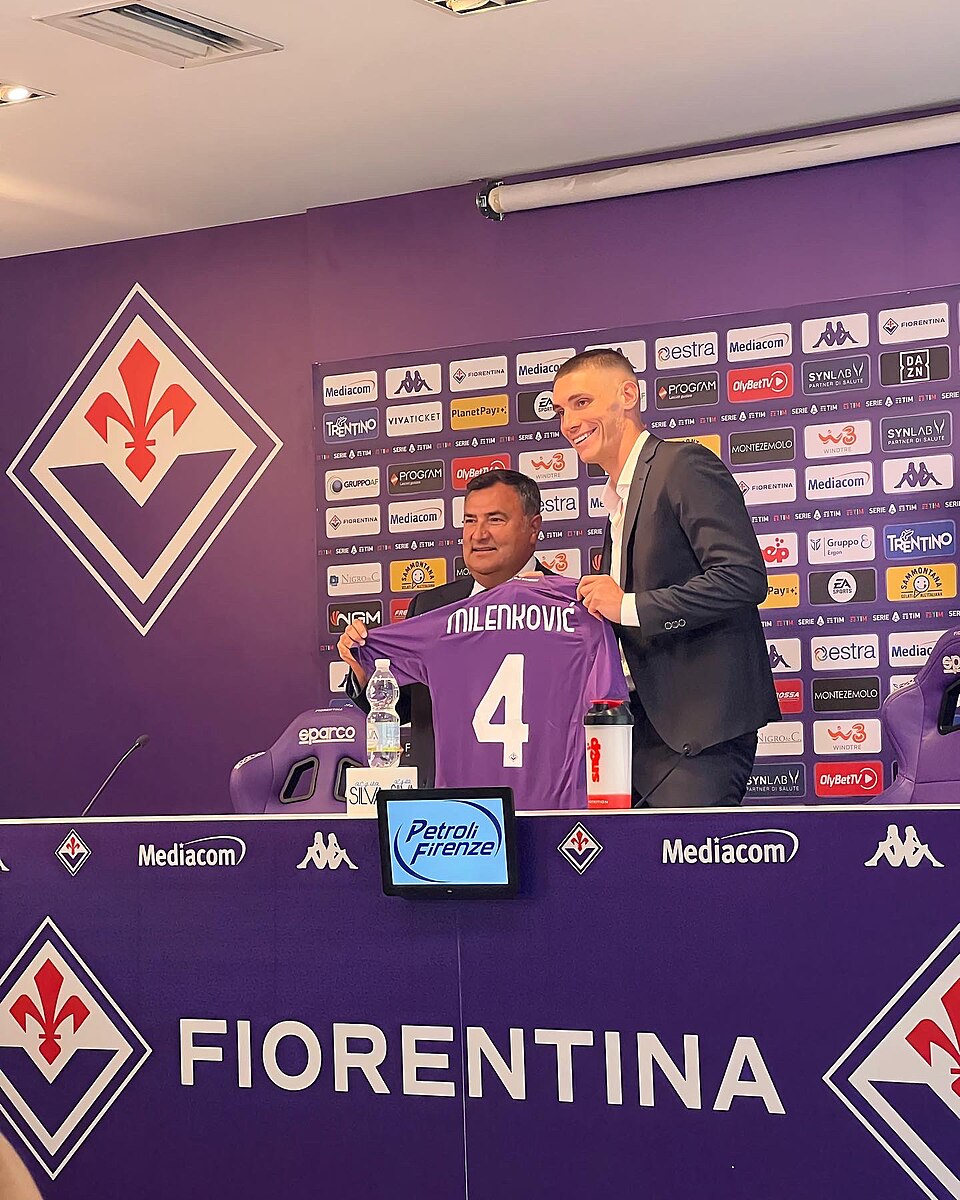 Nikola Milenkovic signing a contract renewal alongside a Fiorentina club director at a press conference