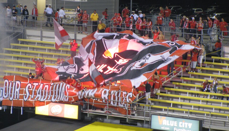 Away supporters holding up banners and flags in a stadium stand
