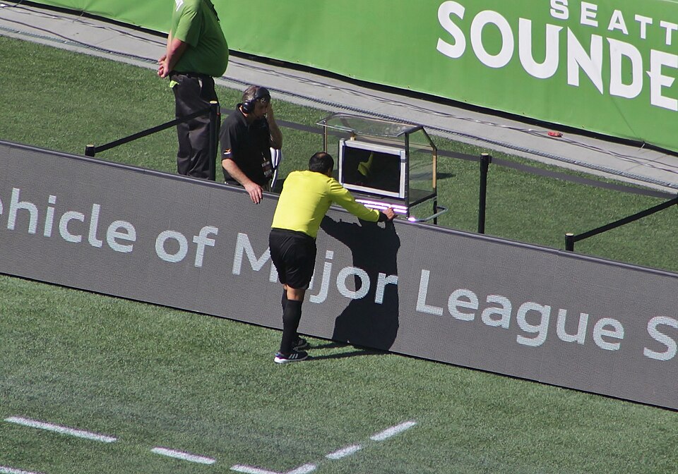 A referee consulting a pitchside video assistant referee monitor during a match