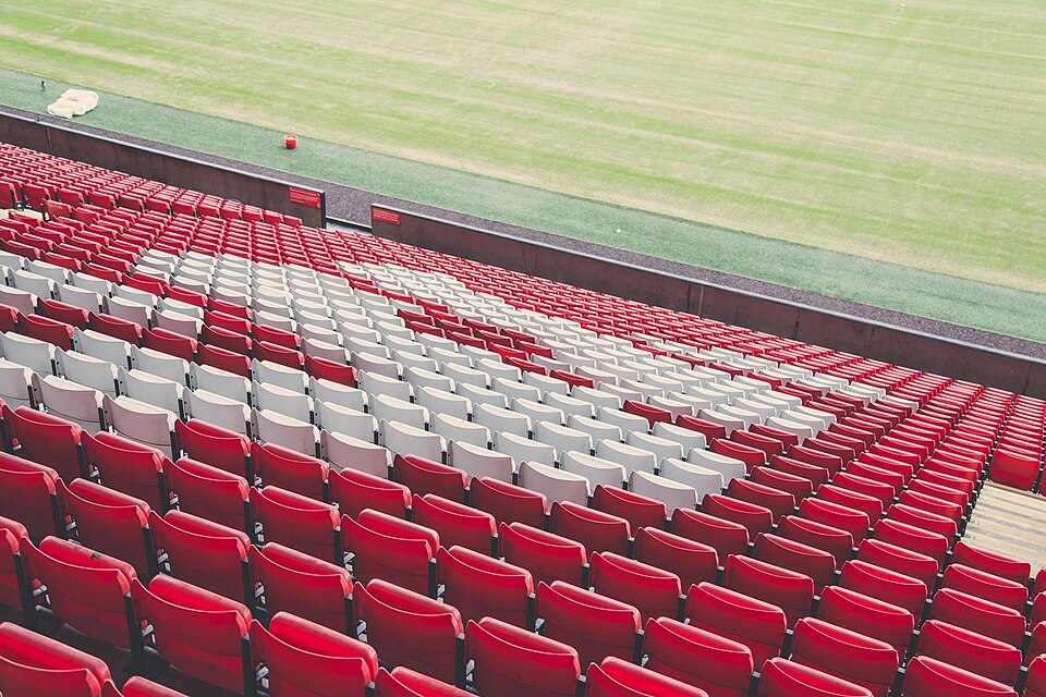 The interior of Anfield seen from the stands, with red seating and floodlights
